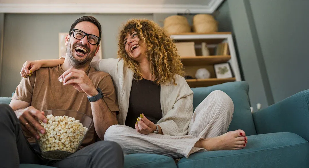 a couple watching tv and eating popcorn